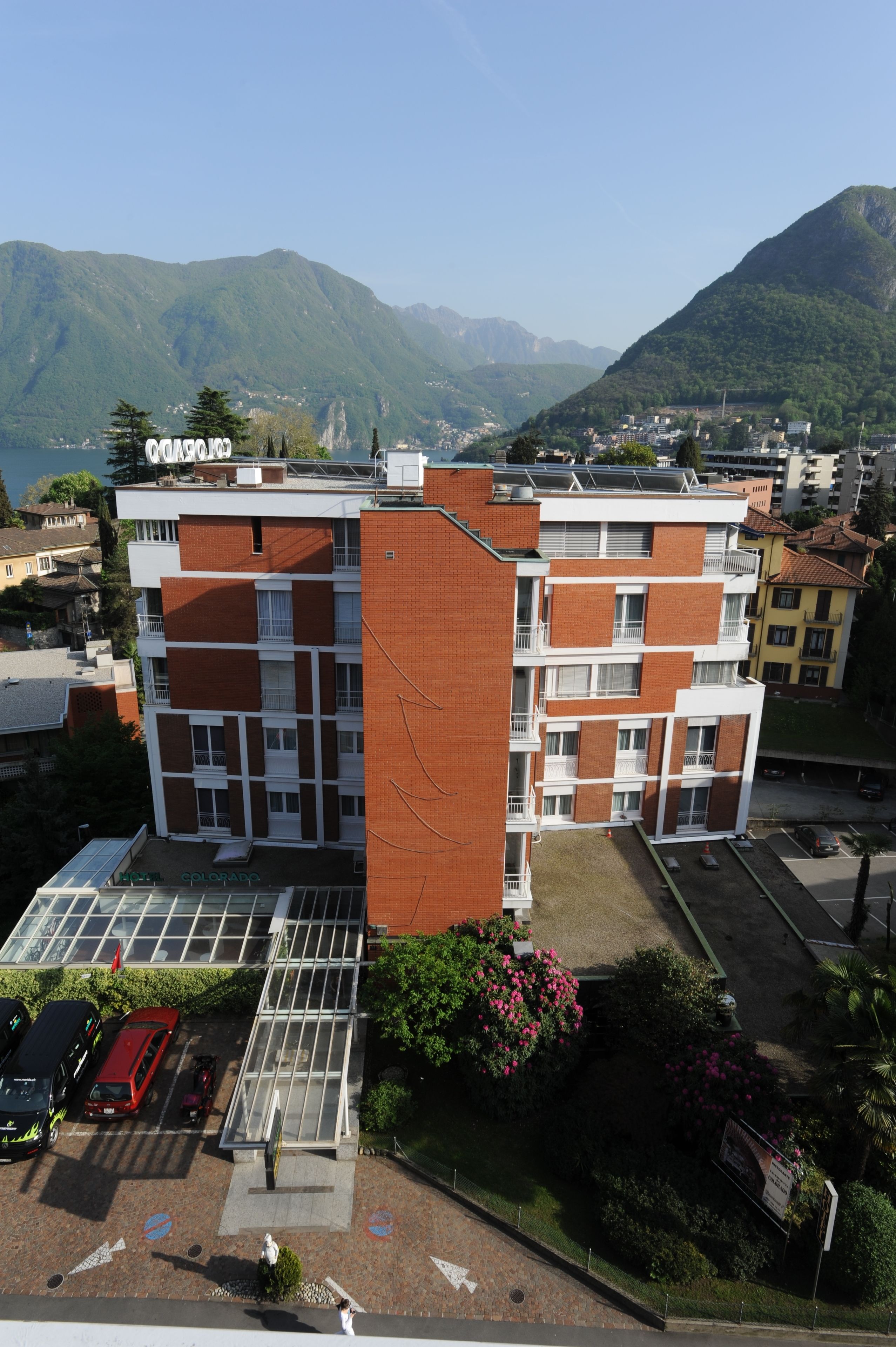 Un immeuble à plusieurs étages, doté d’un toit plat, d’un espace de stationnement et offrant une vue sur les montagnes.