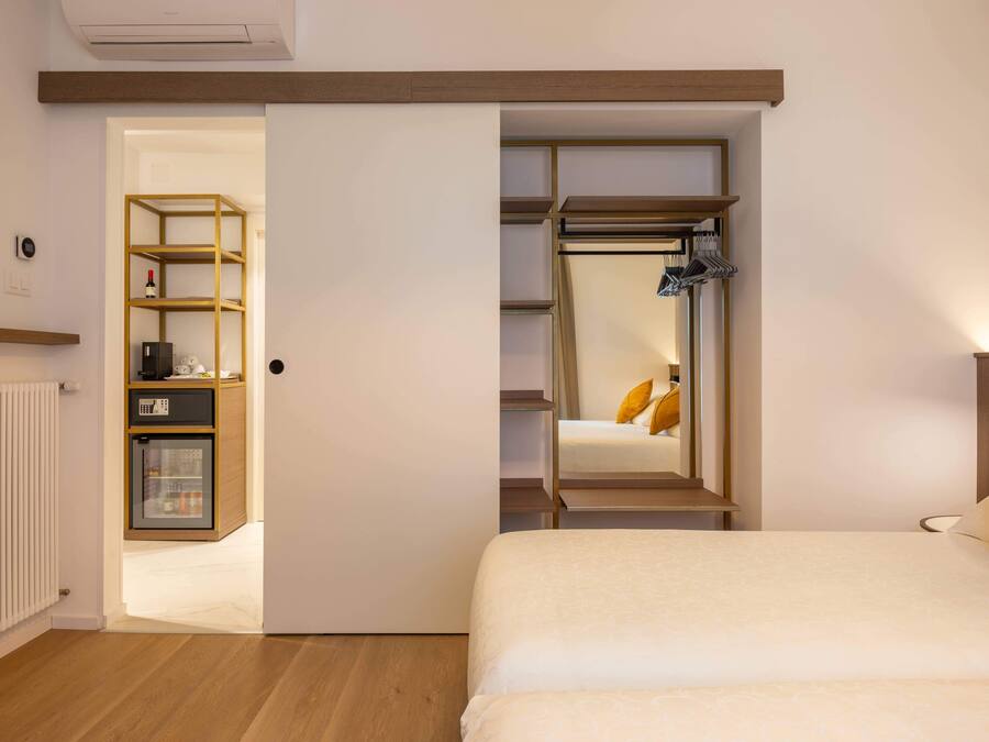 Une chambre à coucher comprenant un lit, une armoire, une étagère et un petit réfrigérateur.
