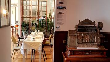 A dining area with a long table set for a meal, a vintage cash register, and a sign indicating WiFi availability.