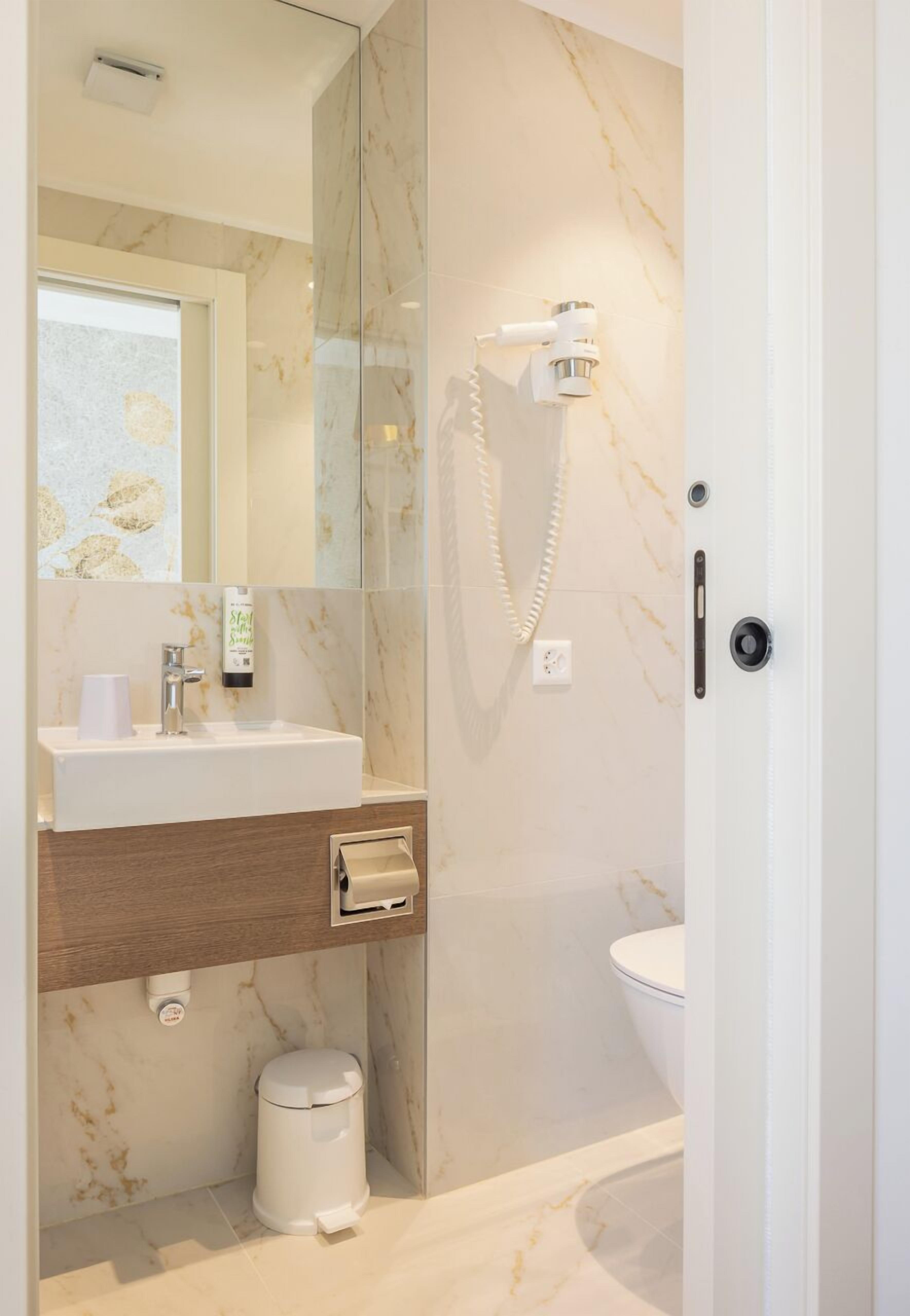Un baño moderno con lavamanos de mármol, ducha de mano y un inodoro.