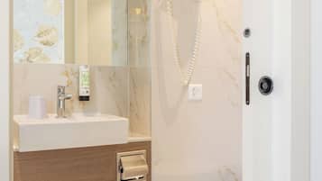 Un baño moderno con lavamanos de mármol, ducha de mano y un inodoro.