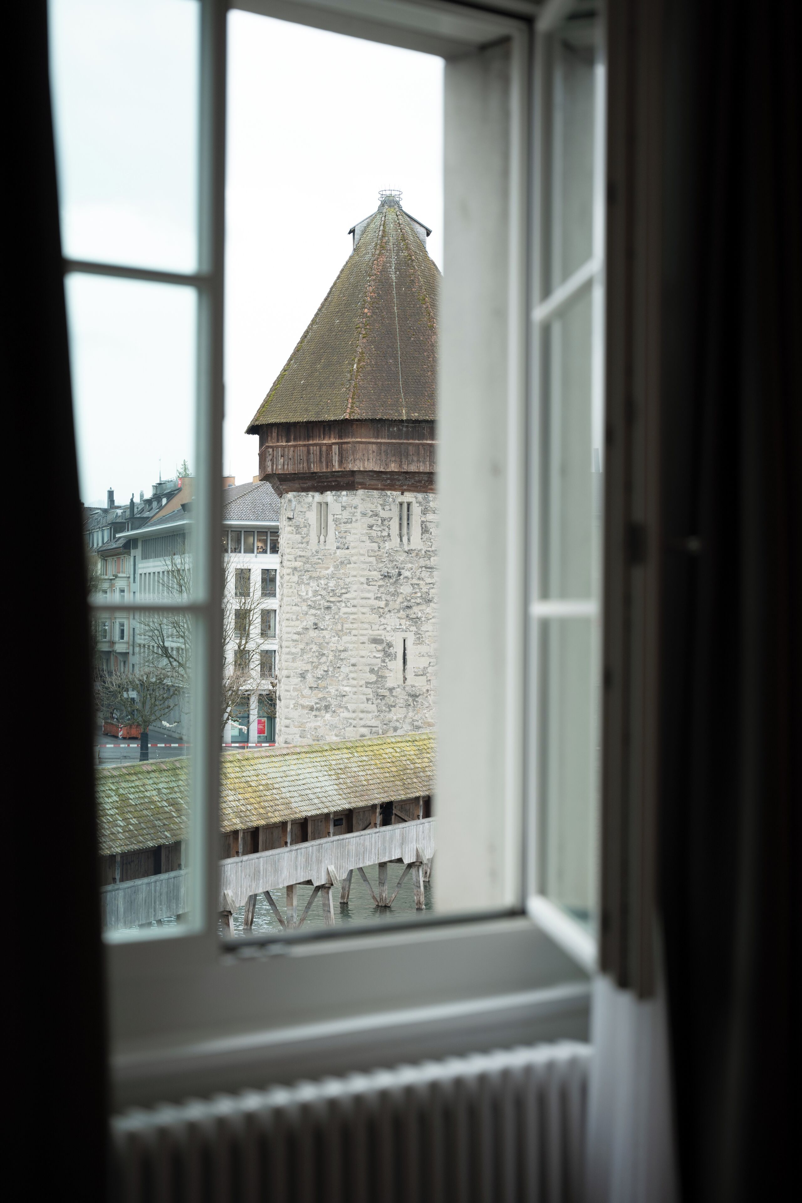 A window view of a historic building with a stone facade and a wooden structure on a bridge.