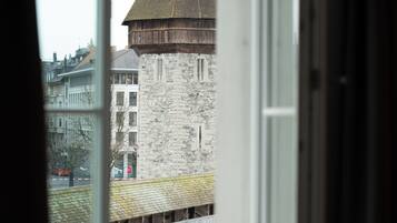 Une vue par la fenêtre sur un bâtiment historique, avec une façade en pierre et une structure en bois, situé sur un pont.