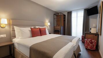 A hotel room with a large bed, two bedside tables, a wardrobe, a TV, and a mirror.