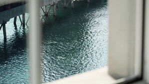 A stone building with a tower, a bridge over water, and a window reflecting the scene. - Des Alpes Luzern (Lucerne)