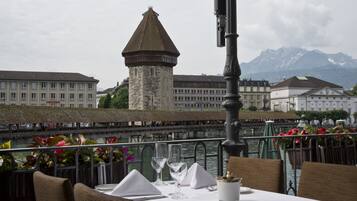 A table set for dining with a view of a historic tower and mountains in the background.