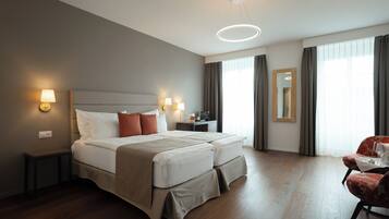 A hotel room with a large bed, bedside tables, a desk, and a chair.
