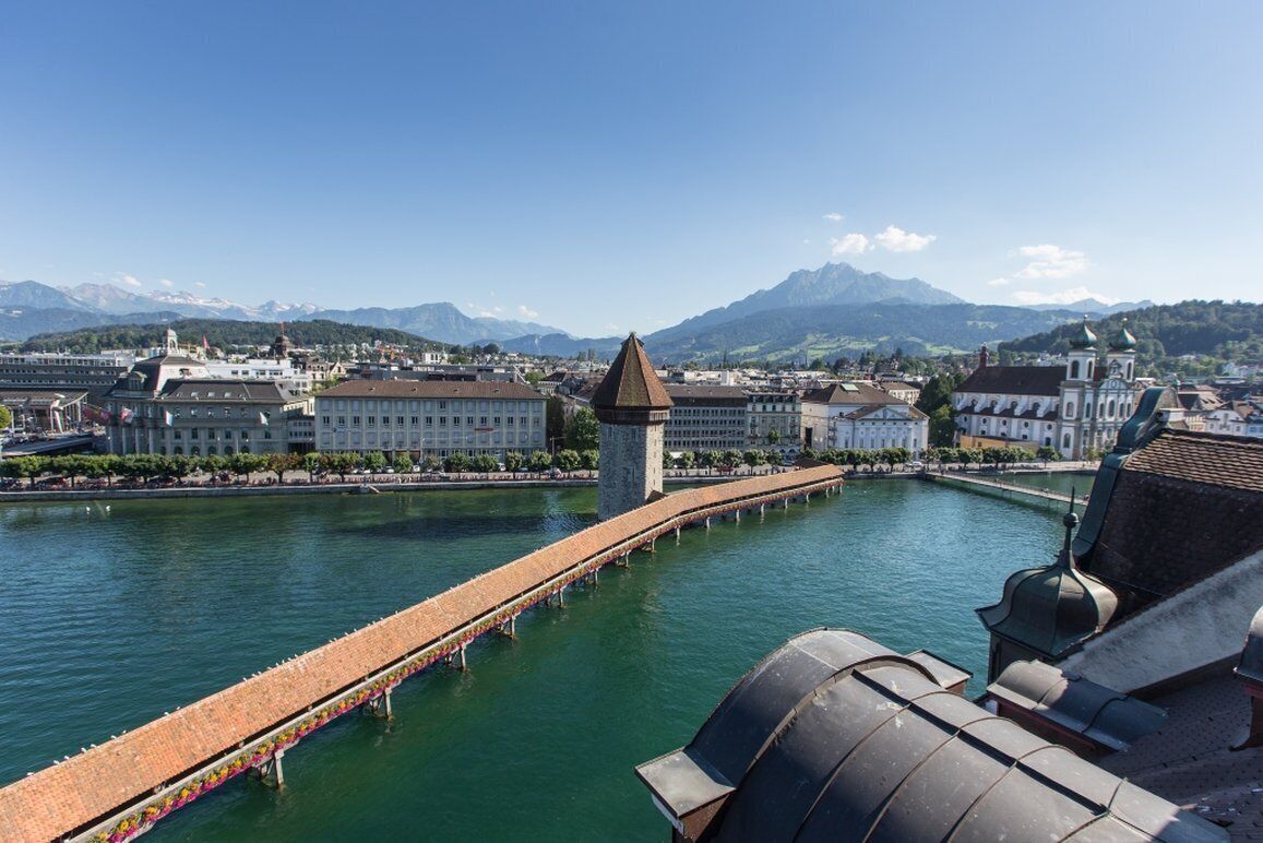 A riverside view with buildings and mountains in the background.