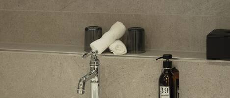 A bathroom with a round mirror, a white sink, a towel, and a soap dispenser.