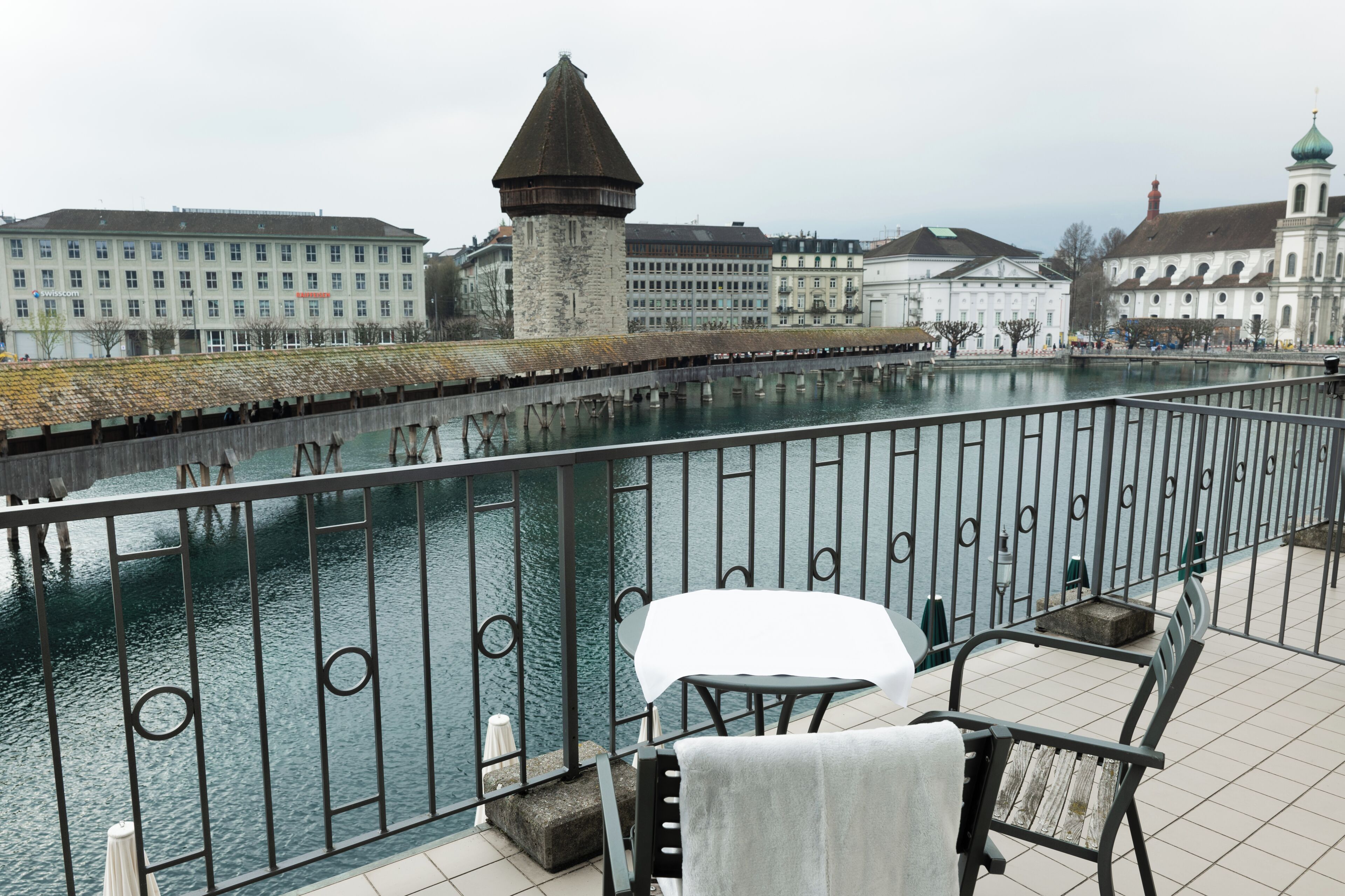 Ein Balkon mit Blick auf einen Fluss, einen Steinturm und Gebäude im Hintergrund.