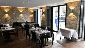A restaurant with stone walls, wooden flooring, and tables set for dining. - Des Alpes Luzern (Lucerne)