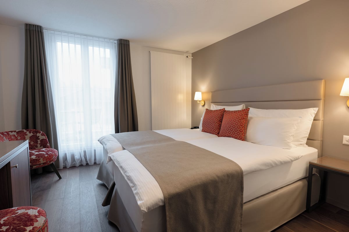 Quarto de hotel com uma cama grande, uma escrivaninha e uma cadeira.