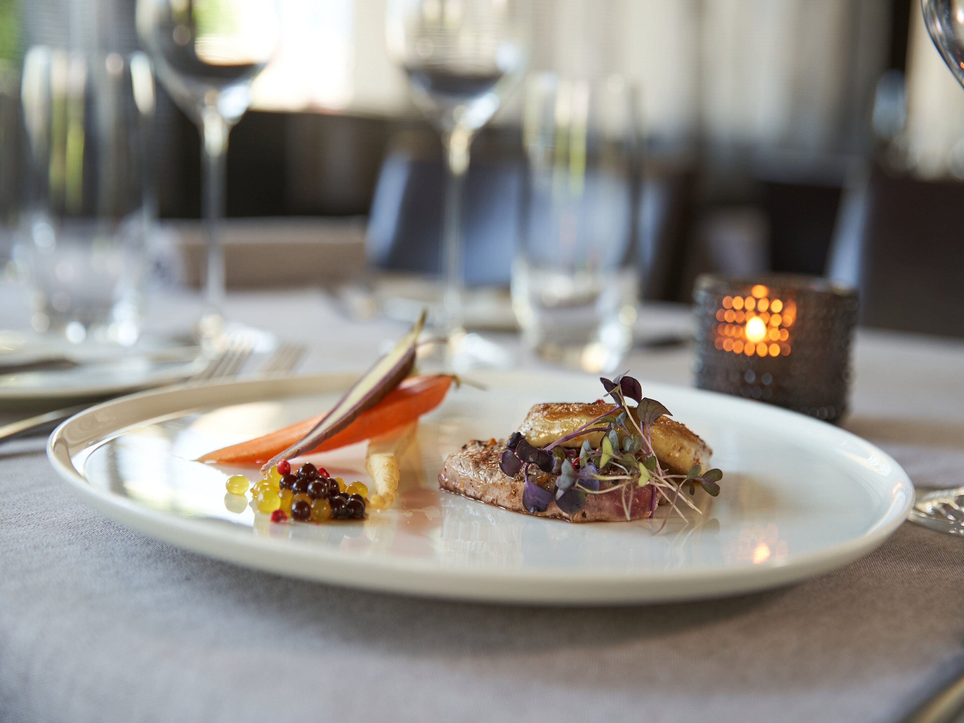 A plate of food with a variety of garnishes and a candle in the background.