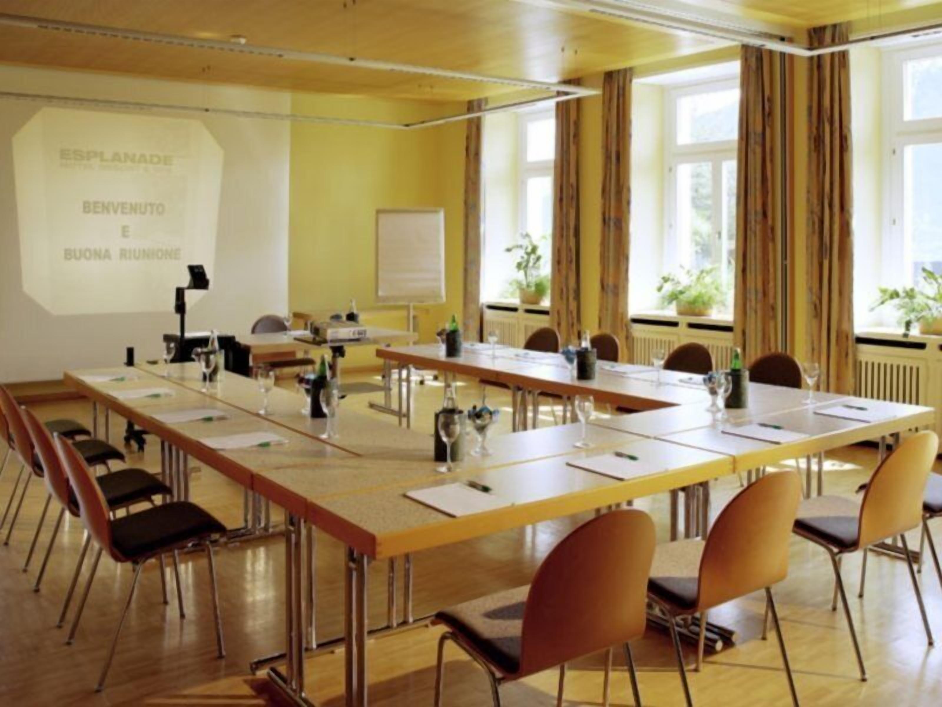 A conference room with a long table, chairs, a projector screen, and a whiteboard.