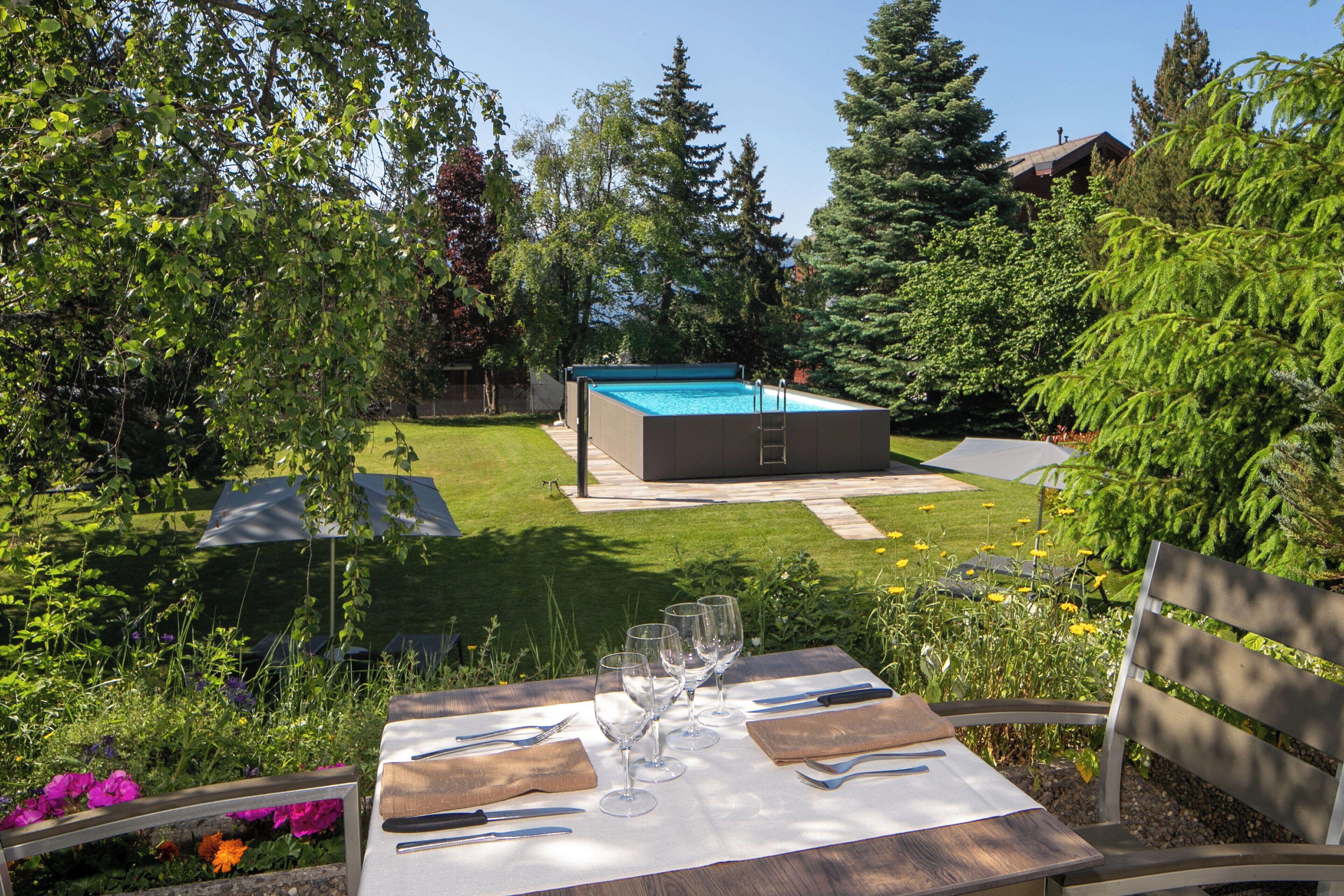 Une piscine avec un escalier, entourée d’une végétation luxuriante et d’une pelouse bien entretenue.