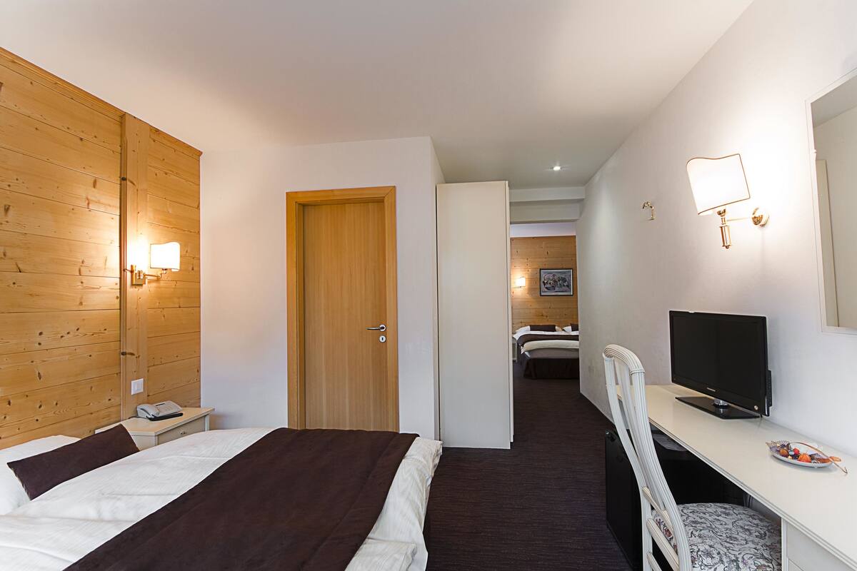 Une chambre d’hôtel comprenant un lit, une table de chevet, une lampe, un bureau avec un ordinateur et une chaise.