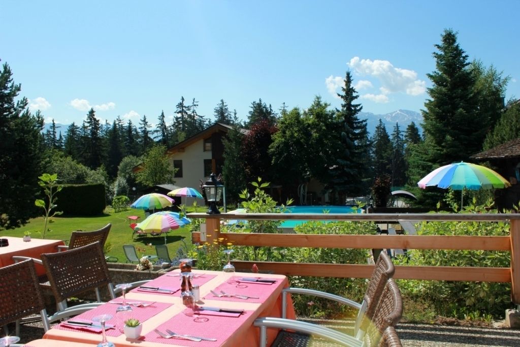 An outdoor dining area with tables and chairs, a pool, and a mountain view.
