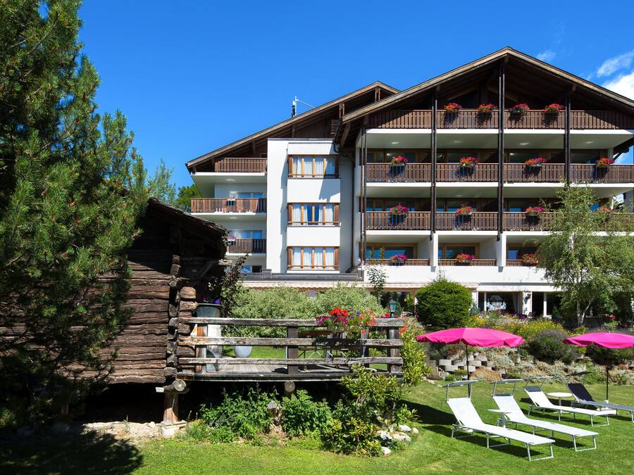 Un hôtel à plusieurs étages doté de balcons, d’une terrasse en bois et d’un espace salon extérieur.