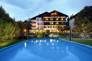 Un hotel con piscina, varios balcones y un jardín bien cuidado.