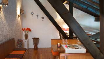 Un comedor acogedor con muebles de madera, un mantel blanco y una vela sobre la mesa.