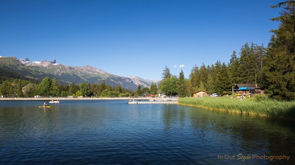 A lakeside view with a dock, boats, and a cabin.