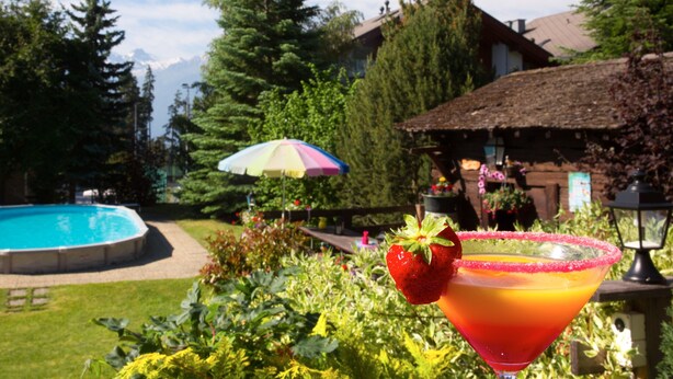 A pool, a house with a thatched roof, and a colorful umbrella. - La Prairie (Crans-Montana)