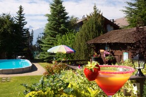 A pool, a house with a thatched roof, and a colorful umbrella.