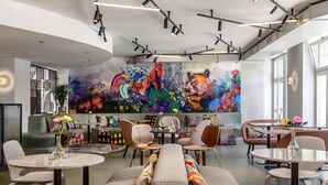 A modern interior with a large abstract mural, multiple seating areas, and contemporary lighting fixtures. -  Sorell Boutique-Hotel City Weissenstein St. Gallen (St. Gallen)