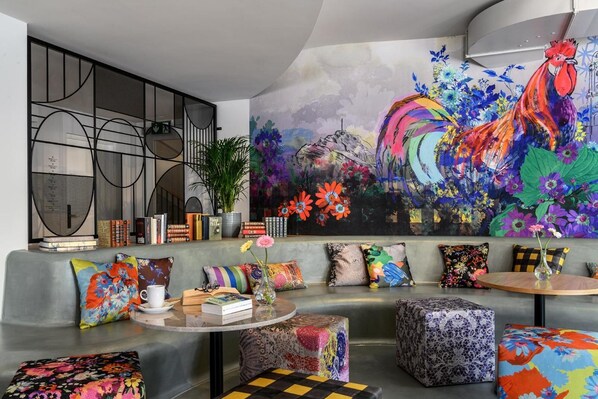A modern living room with a large abstract painting, a bookshelf, and colorful cushions.