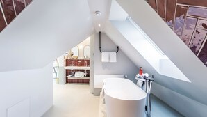 A modern bathroom with a freestanding bathtub, a shower, and a towel rack. -  Sorell Boutique-Hotel City Weissenstein St. Gallen (St. Gallen)