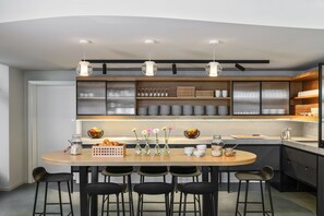 Cocina moderna con una isla central, taburetes de bar e iluminación colgante.
