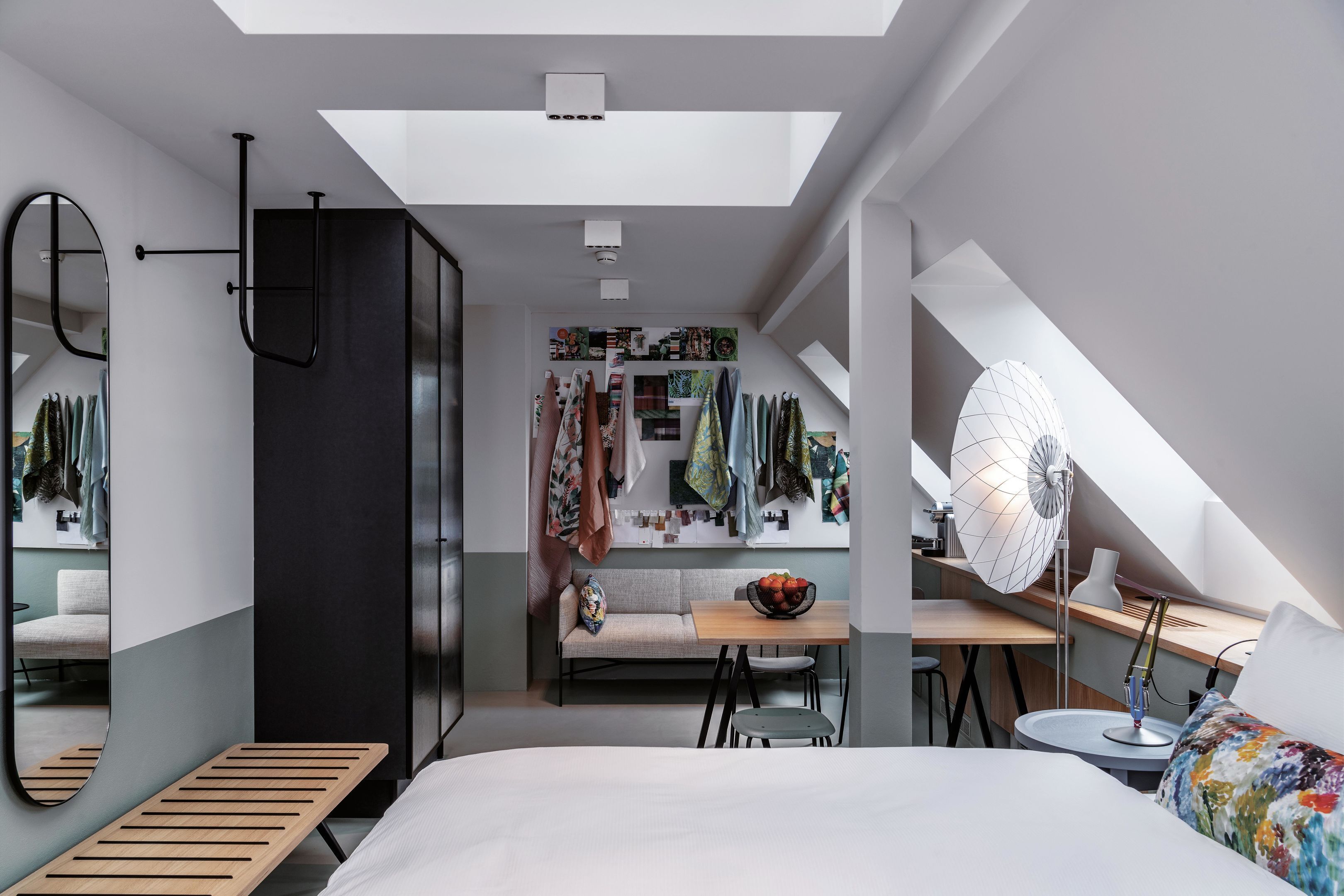 Een moderne slaapkamer met dakraam, een bed, een bureau en een zithoek.
