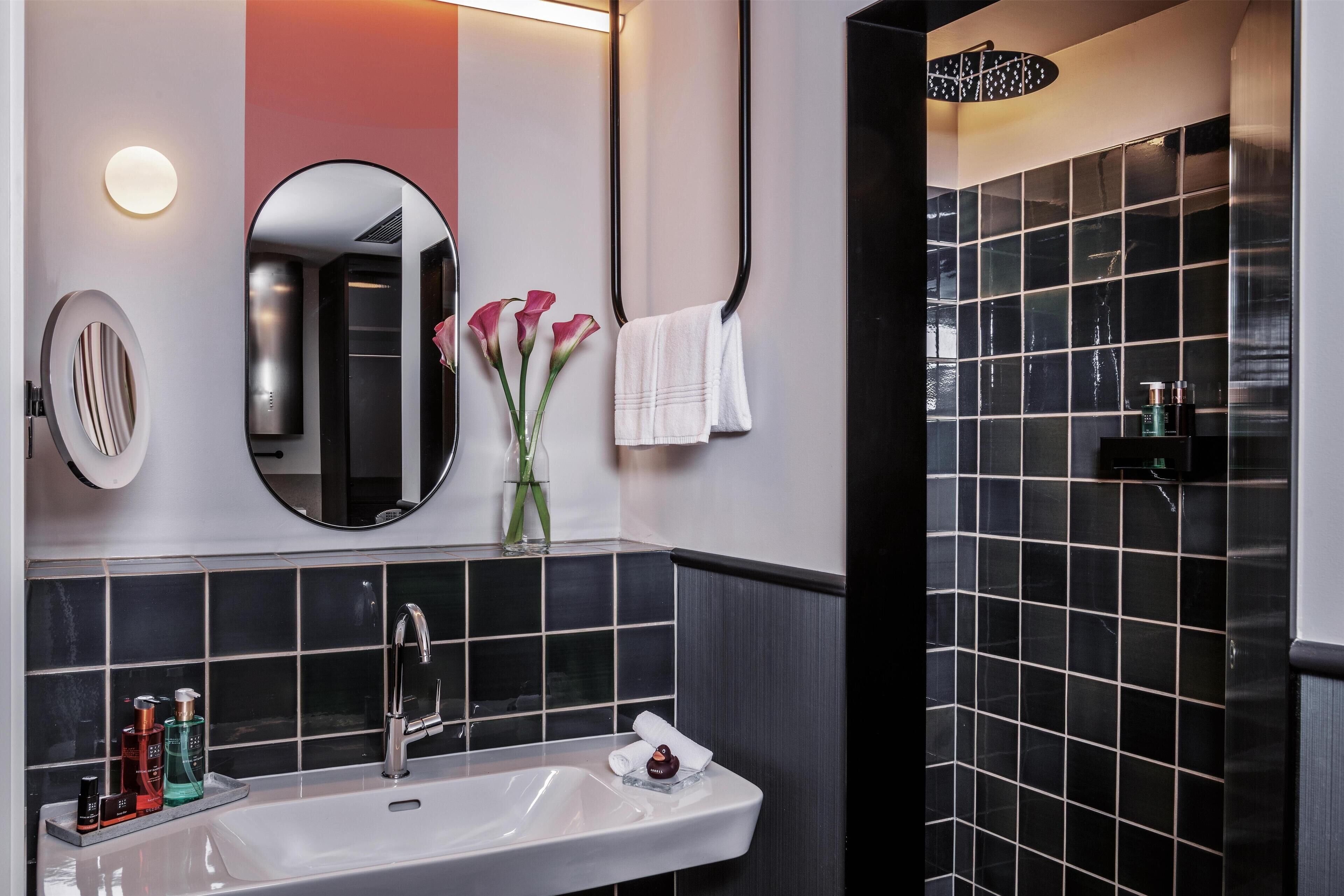 Une salle de bain moderne avec un lavabo blanc, un miroir et un porte-serviettes.