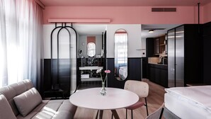 A modern hotel room with a round dining table, a sofa, a bed, and a kitchenette. -  Sorell Boutique-Hotel City Weissenstein St. Gallen (St. Gallen)