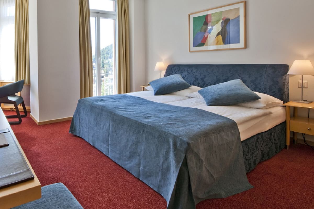 A hotel room with a bed, a desk, and a chair.