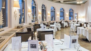 A restaurant with multiple tables set for dining, each with menus and candles. - Schweizerhof Swiss Quality Hotel (St. Moritz)