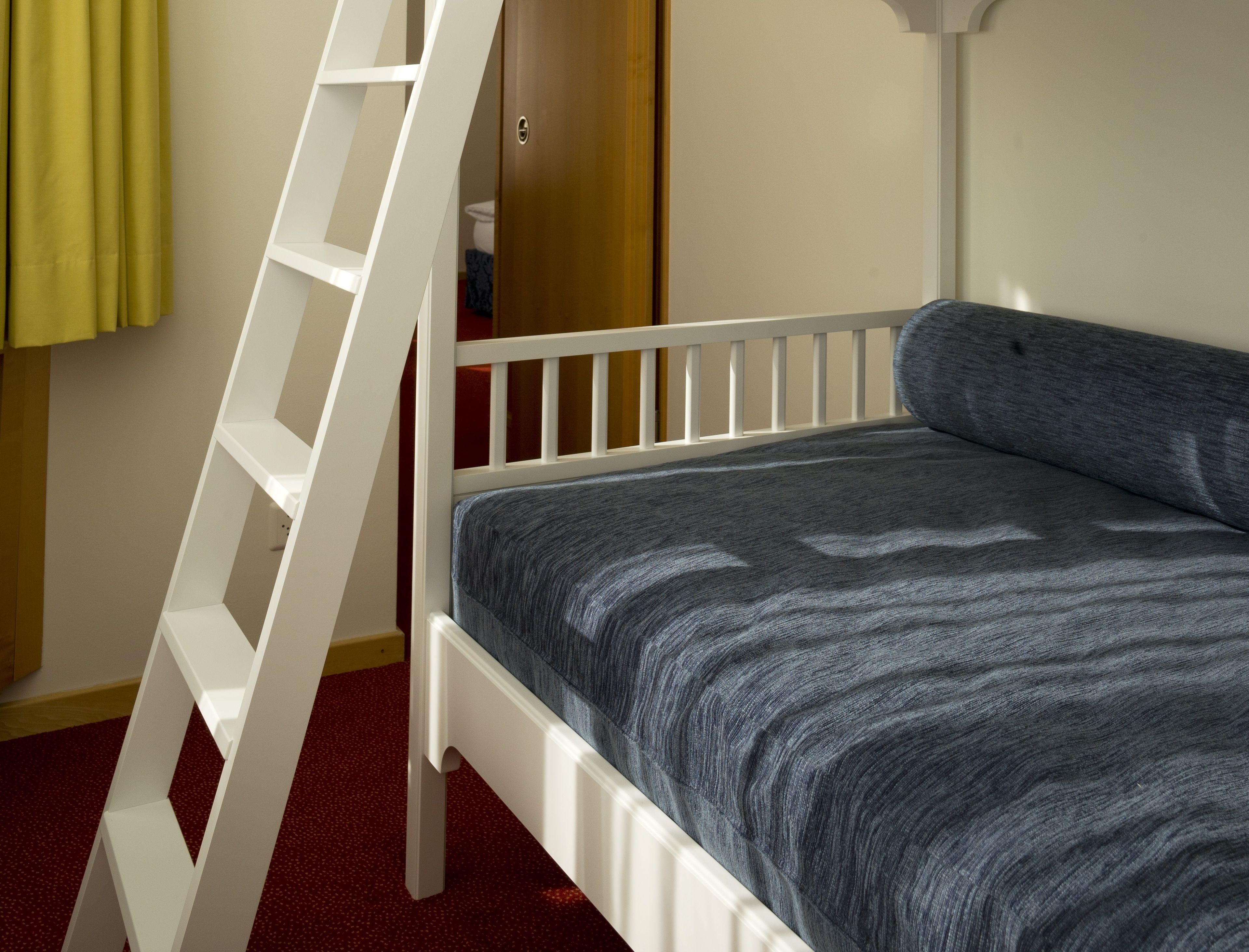 Una cama litera con escalera, una alfombra roja y una puerta con cerradura.