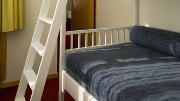 Una cama litera con escalera, una alfombra roja y una puerta con cerradura.