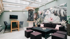 A modern lounge area with a large mural, comfortable seating, and a flat-screen TV.