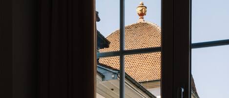 Una ventana con vista al techo de un edificio y una urna decorativa en la parte superior.