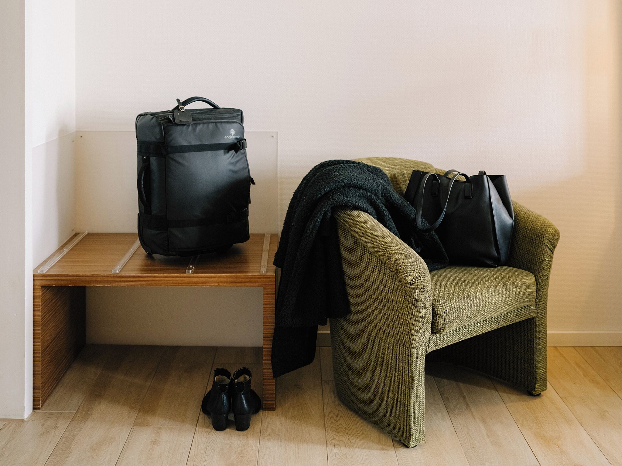 A room with a bench, a chair, a bag, and a pair of shoes.