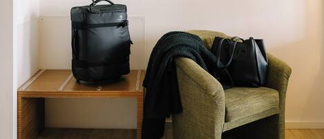 A room with a bench, a chair, a bag, and a pair of shoes.