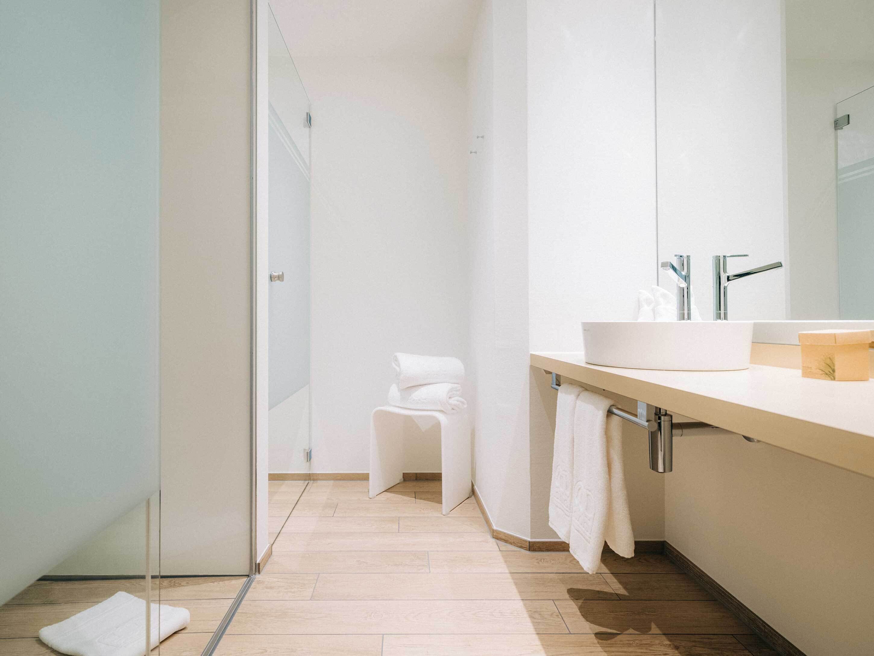A modern bathroom with a large mirror, a sink, and a shower area.