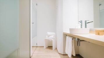 Un baño moderno con un espejo grande, un lavabo y una zona de ducha.