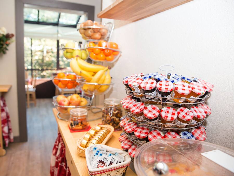 A buffet table with various food items, including fruits, pastries, and jars of spreads.