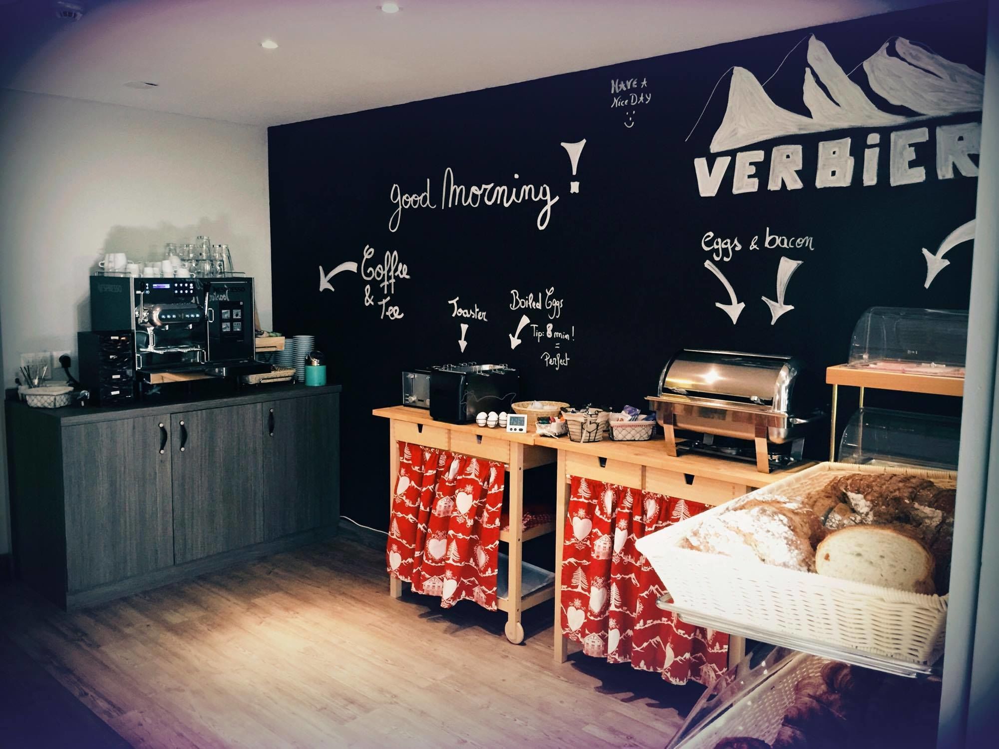 A café with a chalkboard menu, coffee machine, toaster, and a display case with bread.