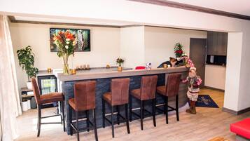 Una cucina moderna con un angolo bar, sgabelli da bar e una pianta decorativa.