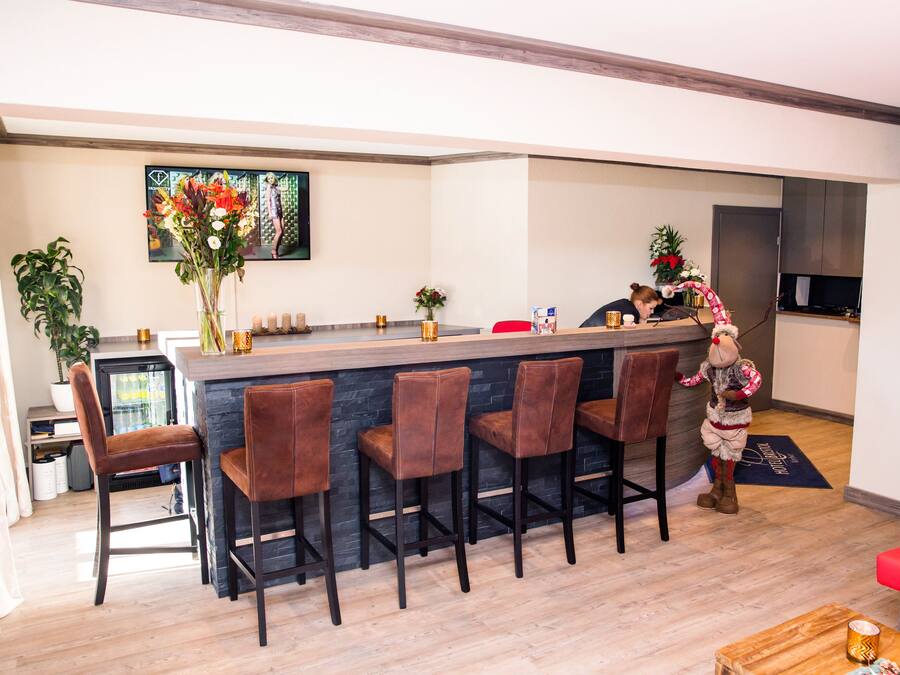 A modern kitchen with a bar area, bar stools, and a decorative plant.