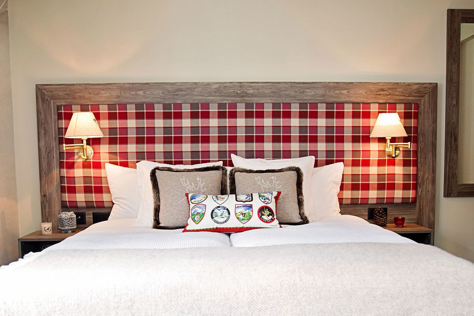 A bed with white bedding, two nightstands, a plaid headboard, and decorative pillows.