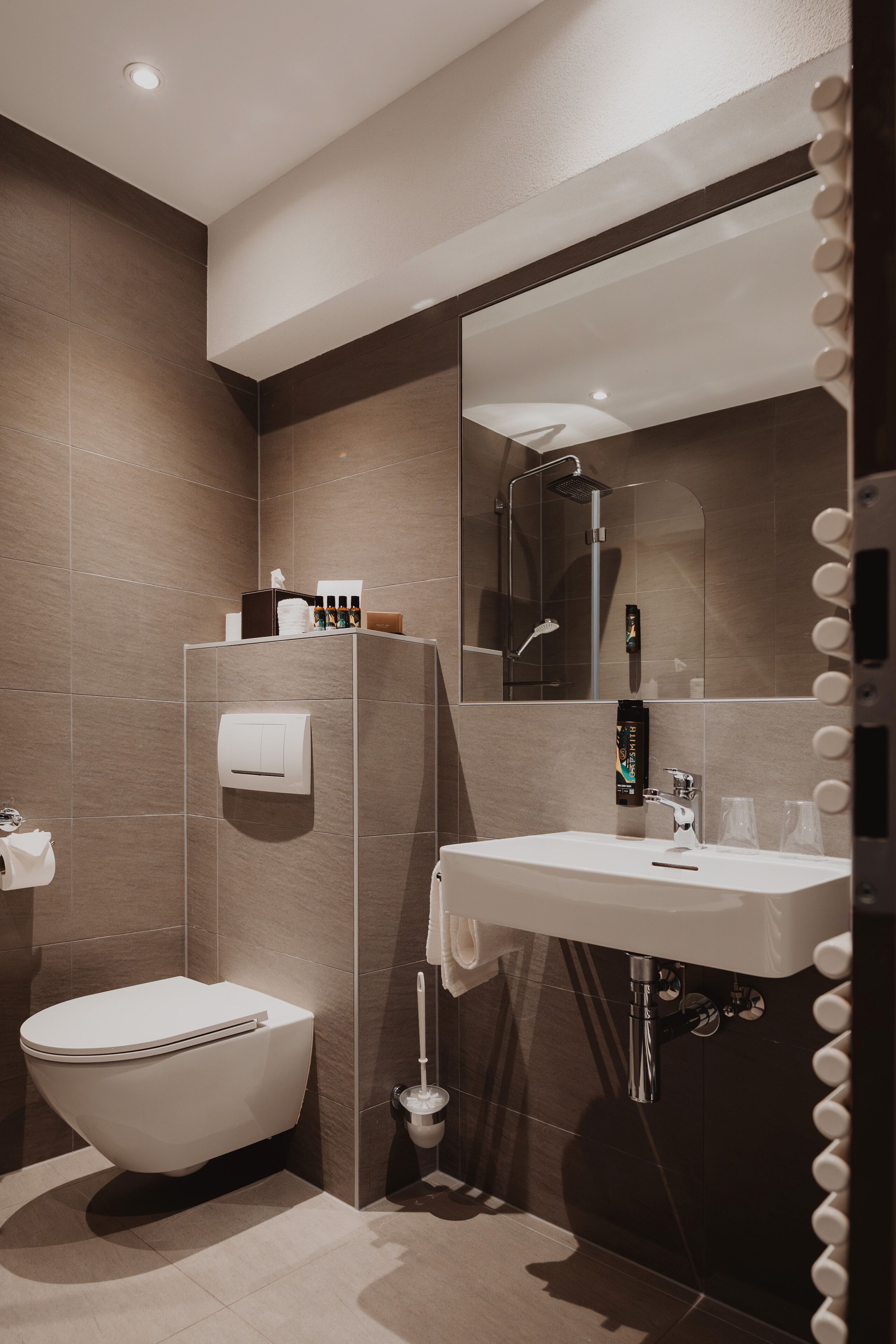 A modern bathroom with a toilet, sink, and mirror.